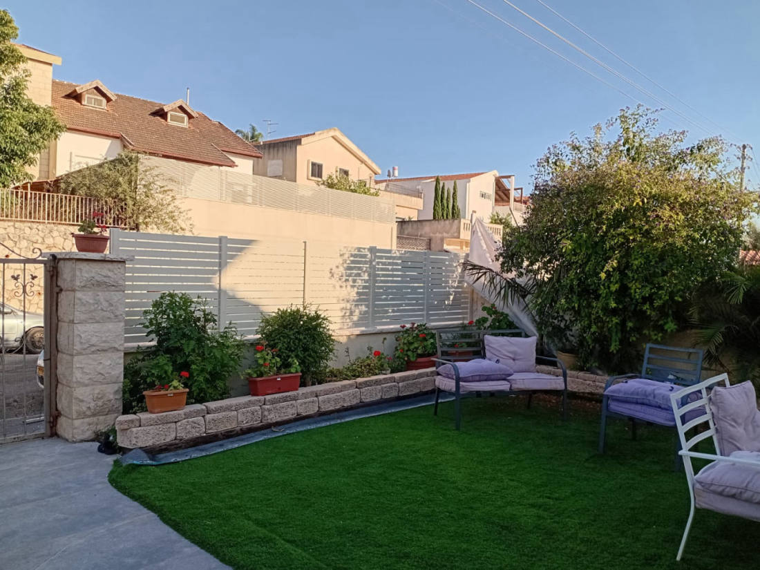 גדר אלומיניום לבנה בפינת גינה עם דשא ופינת ישיבה · פרויקט של אביאל